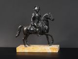 une statue antique en bronze représentant un homme à cheval, posée sur un socle en marbre