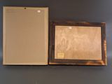painting in a wooden frame on a wall next to a cardboard box