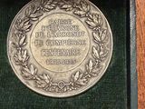 a silver medal in a green box on a wooden table