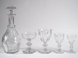 cinq verres à vin et une carafe posés sur une table