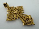a close up of a gold pendant on a white surface