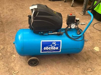 a blue air compressor sitting on the ground in the dirt