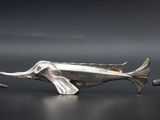 three silver figurines of animals walking on a black surface