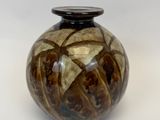 un vase brun et noir posé sur une surface blanche