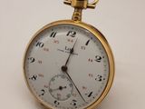 une petite montre de poche en or posée sur une surface blanche