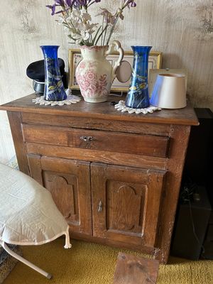 un petit meuble en bois avec des vases, devant lequel se trouve une chaise