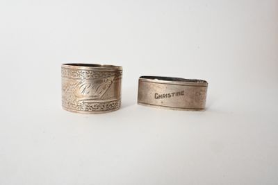 two silver rings with engraved names on them sitting next to each other
