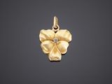a yellow gold flower pendant with a diamond in the center