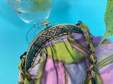 a purple and green purse sitting on top of a blue table