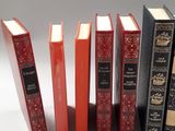 several books are lined up in a row on a white surface