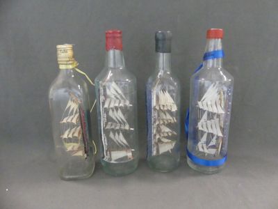 quatre bouteilles en verre contenant différents types de voiliers
