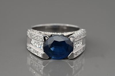 une bague sertie d'un saphir bleu et de diamants posée sur une surface réfléchissante