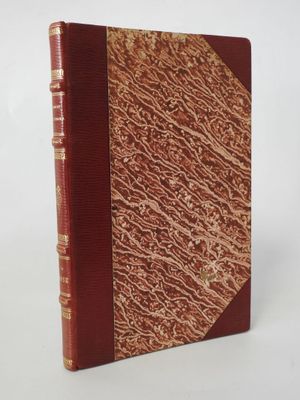 an old book with a red cover sitting on top of a white surface