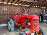 un tracteur rouge garé dans une grange au toit en bois