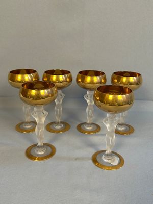 six verres à vin dorés, bordés d'or, posés sur une table blanche