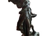 bronze statue of a woman holding a bird on top of a table