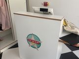 une boîte blanche ornée d'un logo, posée sur un sol à damier noir et blanc