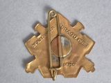 an image of a gold pin with a compass on it