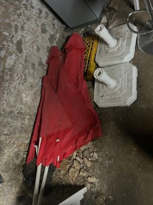 a red umbrella sitting on the ground next to a trash can