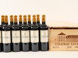six bottles of wine in a wooden box next to a glass of wine