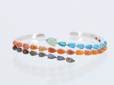 bracelet manchette en argent orné de pierres multicolores, sur un fond blanc