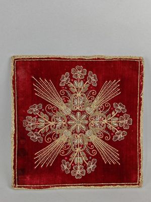 un gros plan sur un tissu rouge et doré orné d'une croix