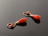 pair of coral and gold earrings on a black surface