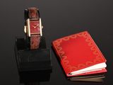 a watch and a red book on a black table