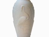 a white vase with a bird on it on a white surface