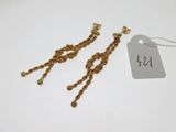 une paire de boucles d'oreilles en or avec une étiquette de prix sur fond blanc