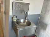 a sink in the corner of a bathroom with a water dispenser on the wall