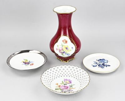 un vase rouge, un bol et une assiette posés sur une table