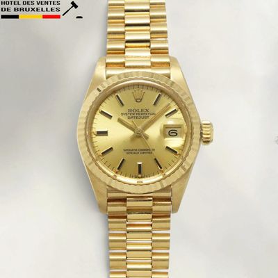 an image of a gold rolex watch sitting on a white surface