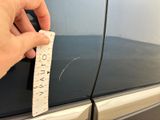 a hand that is holding a piece of paper near a car door