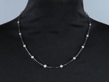 une femme portant un t-shirt noir et un collier de perles