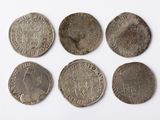six silver coins of different sizes and shapes on a white surface