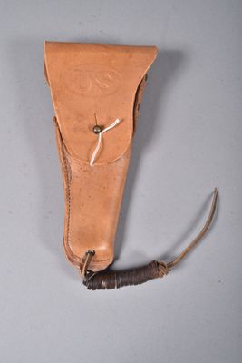 un vieux fourreau en cuir contenant un couteau, posé sur une surface grise