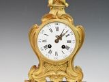 a gold clock with a bird on top of it