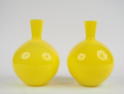 une paire de vases jaunes posés sur une surface blanche, sur fond blanc