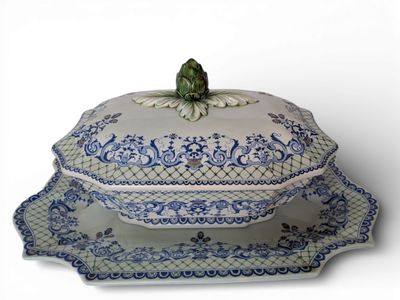 un plat blanc et bleu sur lequel est posée une grenouille
