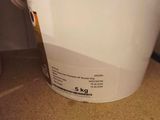 a white bucket sitting on the floor next to a toilet