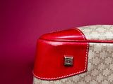 the red and white handbag is sitting on a pink surface