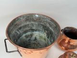 two copper pots and a copper jug on a white table
