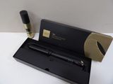 un stylo noir dans une boîte noire, à côté d'un flacon de parfum