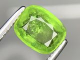 une image montrant un gros plan d'un diamant vert tenu par une paire de pinces