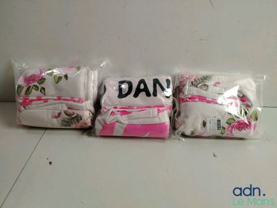 trois sacs de vêtements pour bébé posés sur une table blanche