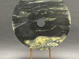 sculpture of a black and yellow marble disc on a wooden stand