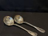 two silver spoons sitting on top of a black table