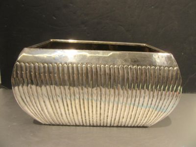 un vase en argent posé sur une table, sur fond noir