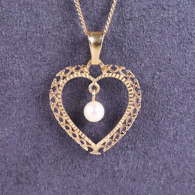 un gros plan d'un pendentif en forme de cœur contenant une perle